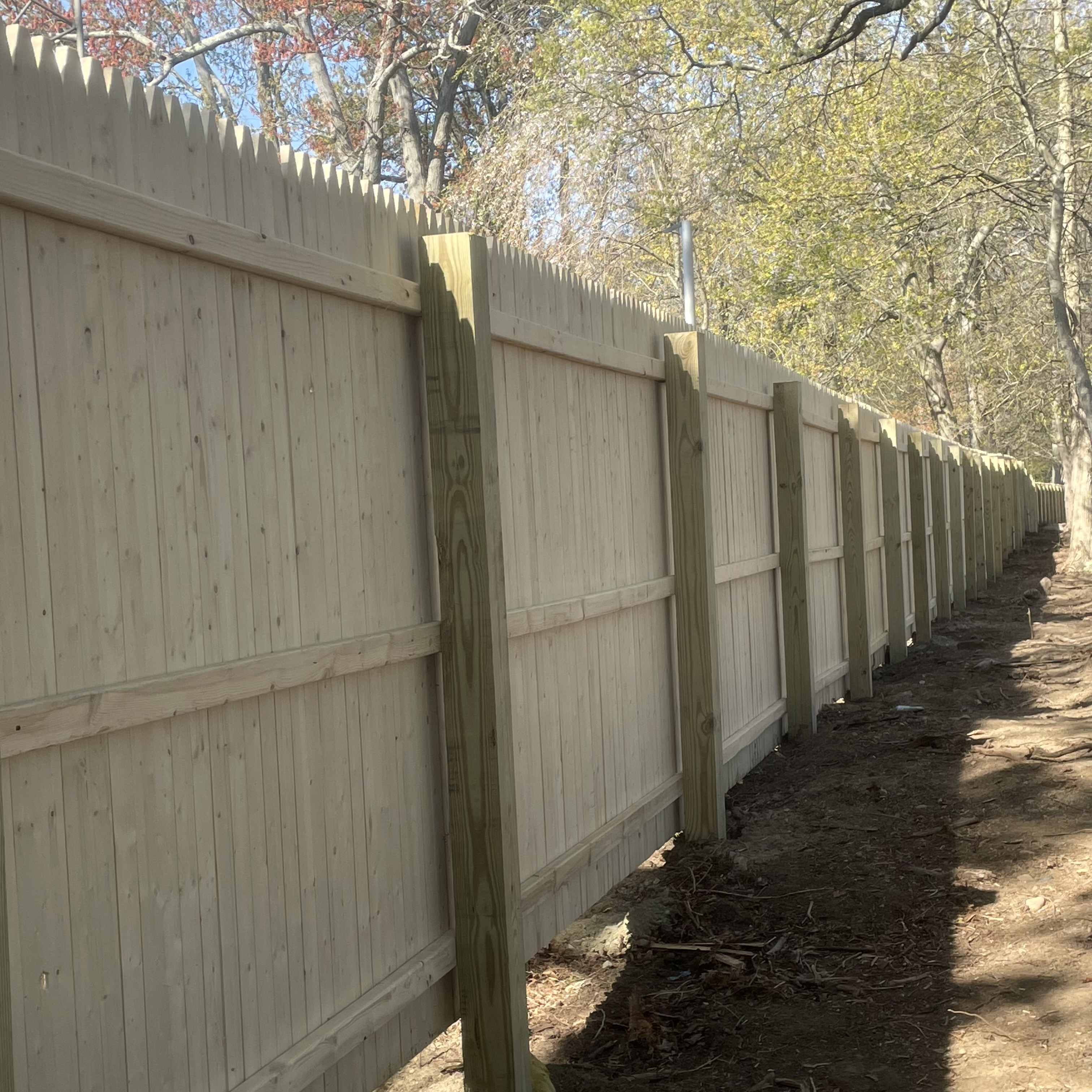 Long wooden fence installed by New Haven Fence LLC along a Connecticut property