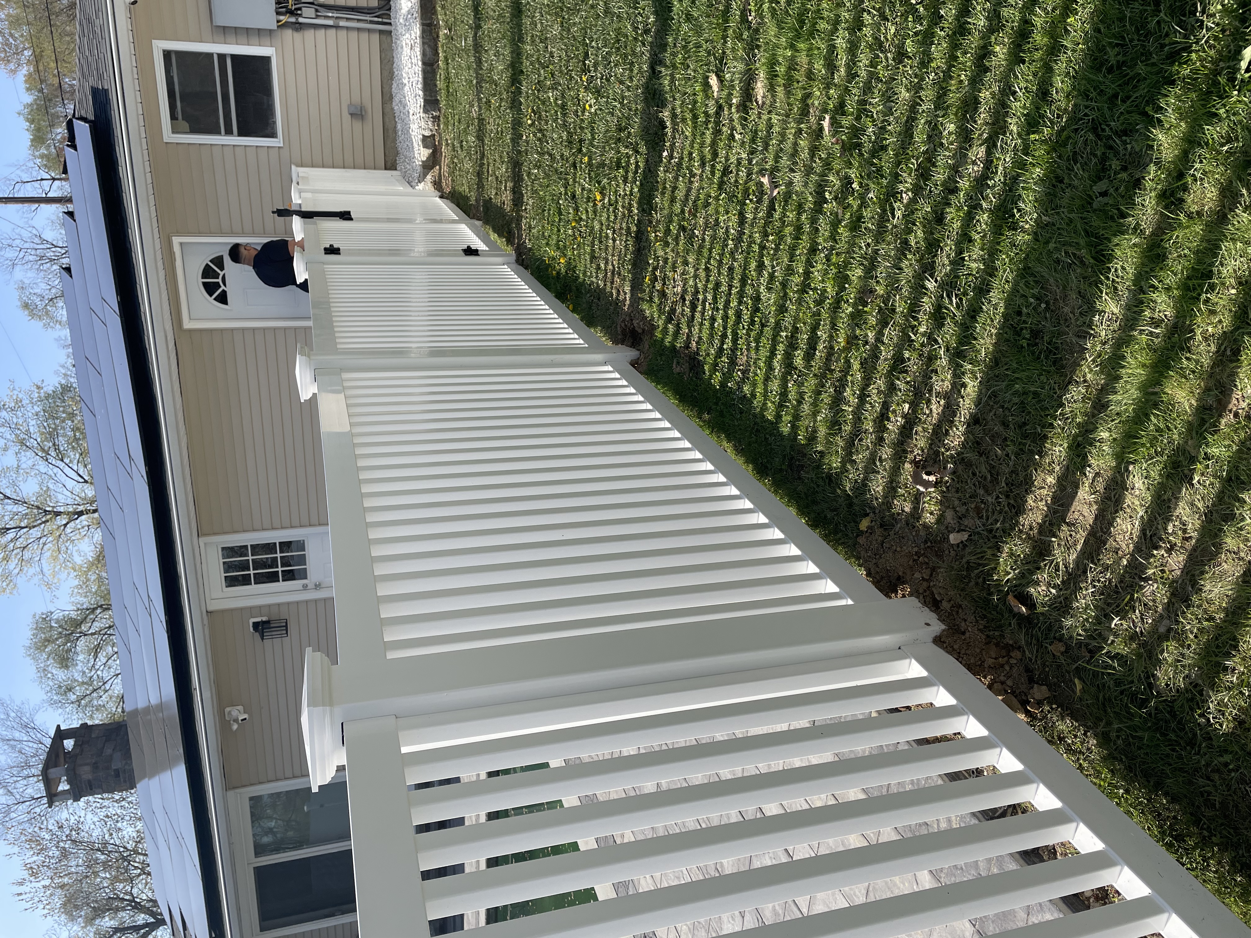 White fence in front of a house with solar panels on the roof