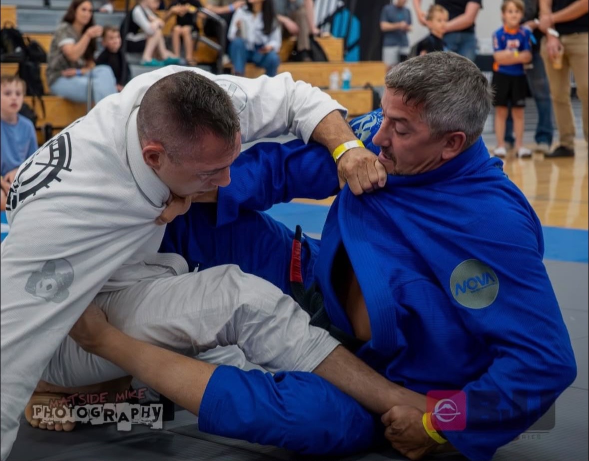 Two Brazilian jiu jitsu competitors battling for grips during an open-guard exchange.