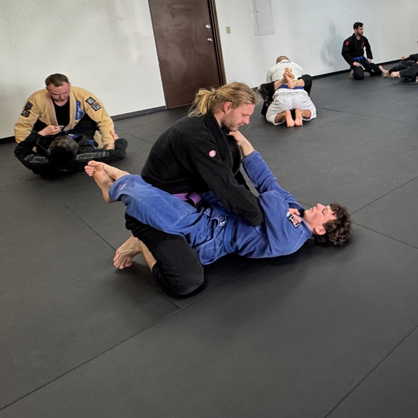 Several pairs of students drill jiu jitsu techniques together at 608 Jiu Jitsu