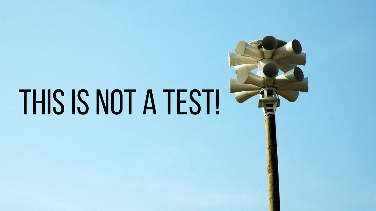Civil defense siren against a blue sky with the words “This is Not a Test!”