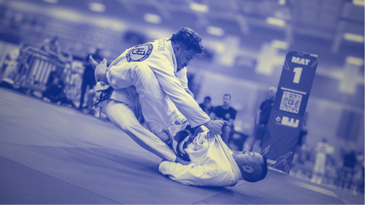 Two Brazilian jiu jitsu competitors adjust their grips and balance during a guard exchange at a tournament.