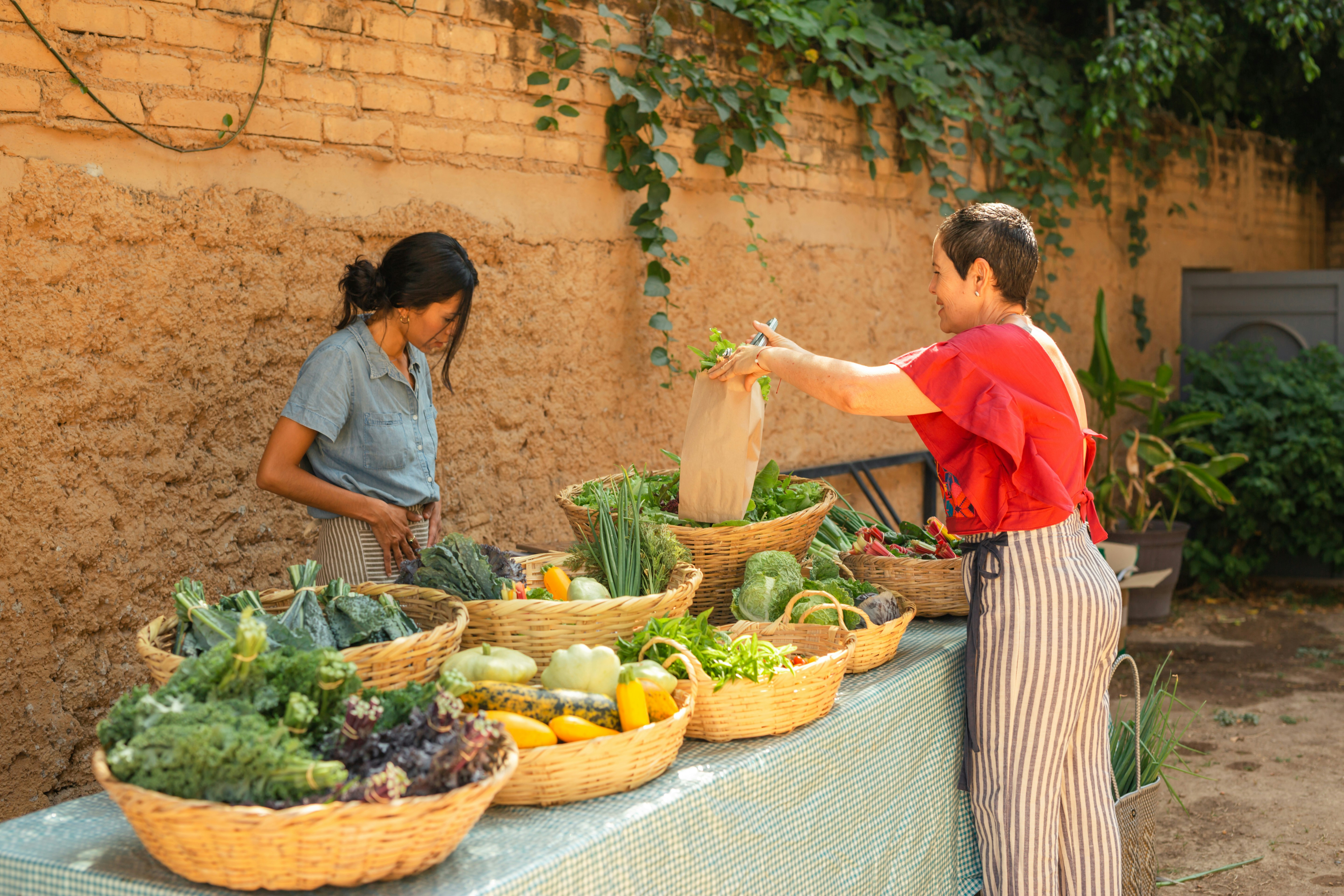 a woman stood opposite a market table full of vegetables