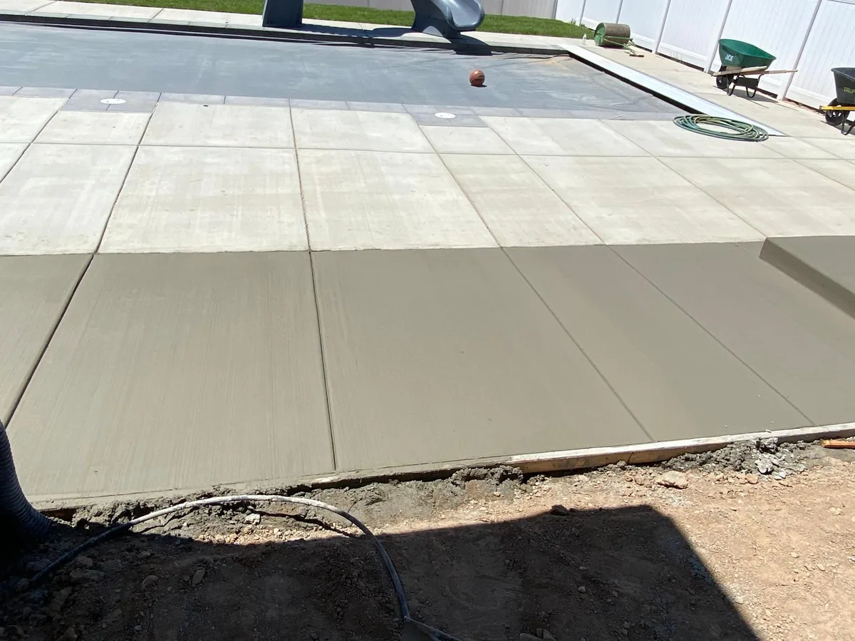 Fresh broom-finished concrete flatwork beside an existing patio