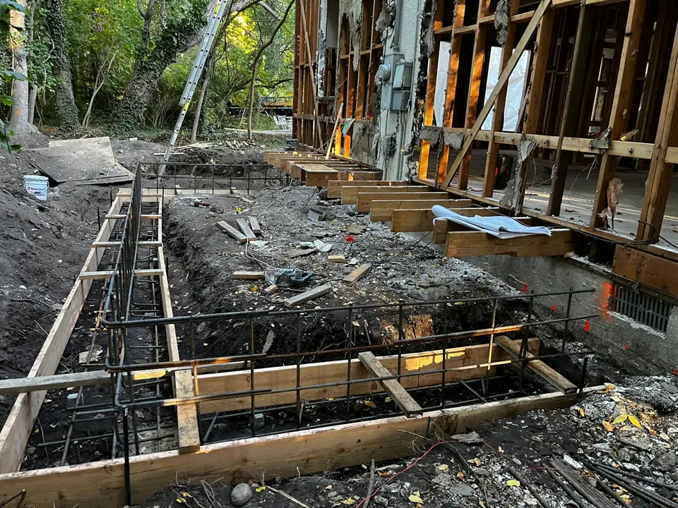 Concrete footing formwork and steel reinforcement beside an existing home