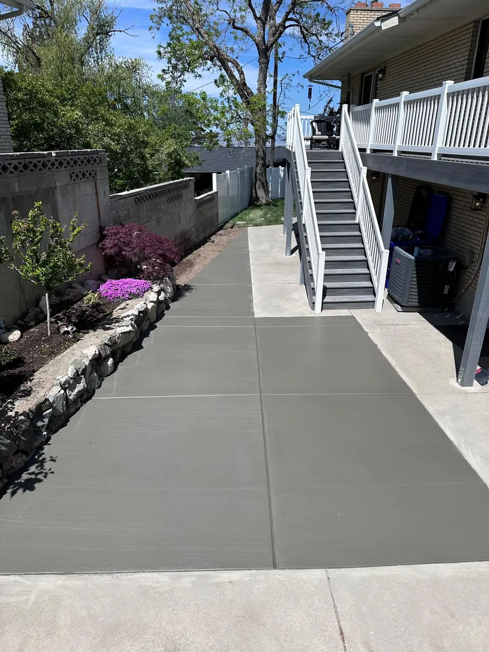 New concrete walkway and patio around a backyard staircase