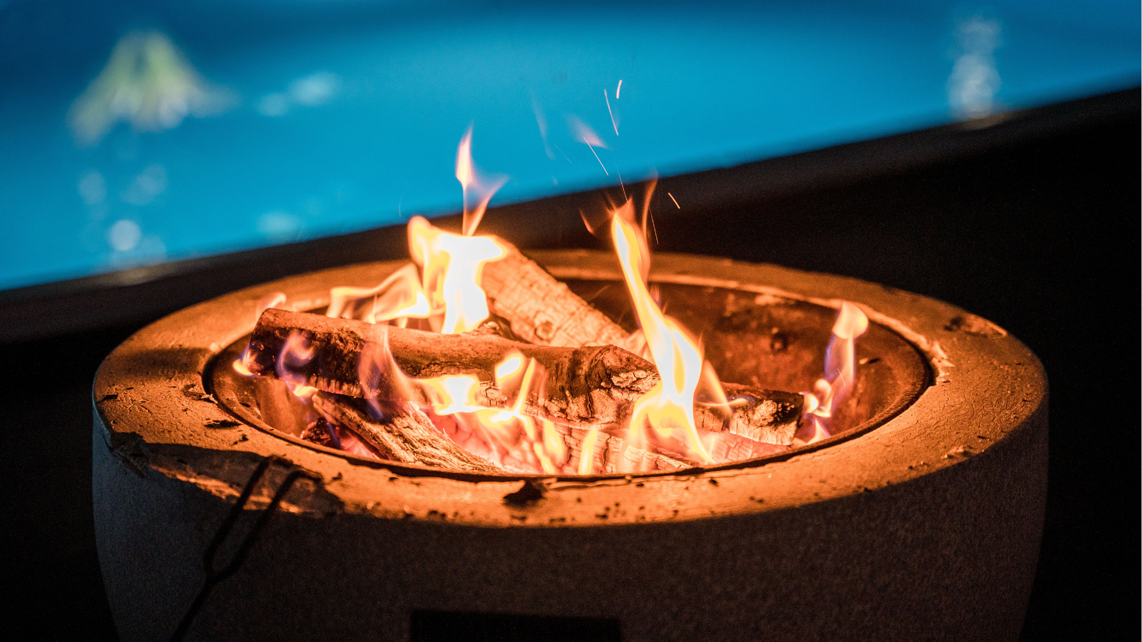 fire bowl in front of a pool at night