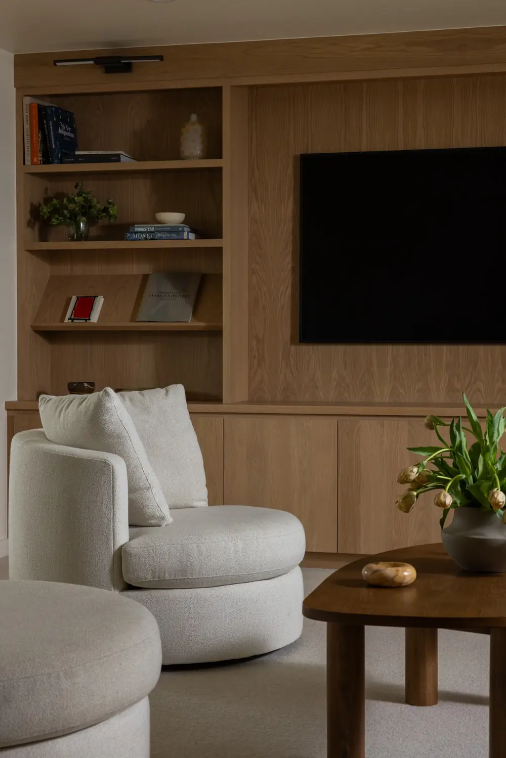 Oak built-in shelving and upholstered lounge chairs in a remodeled living room
