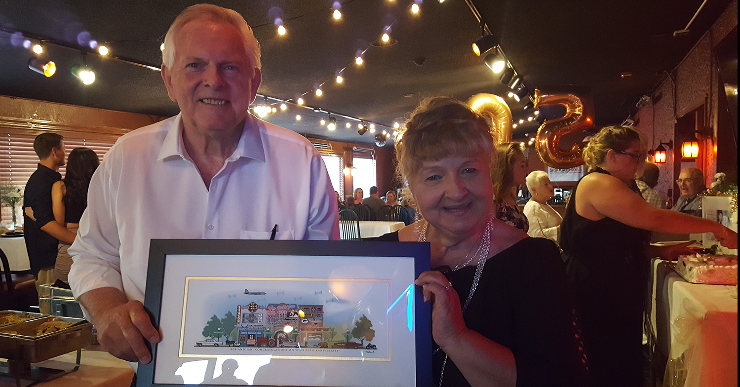 Bob and Jan holding their framed Your Memory Lane 25th-anniversary street print.
