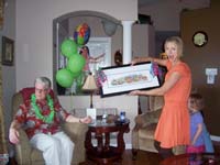 A woman unveiling a framed gift at a family celebration