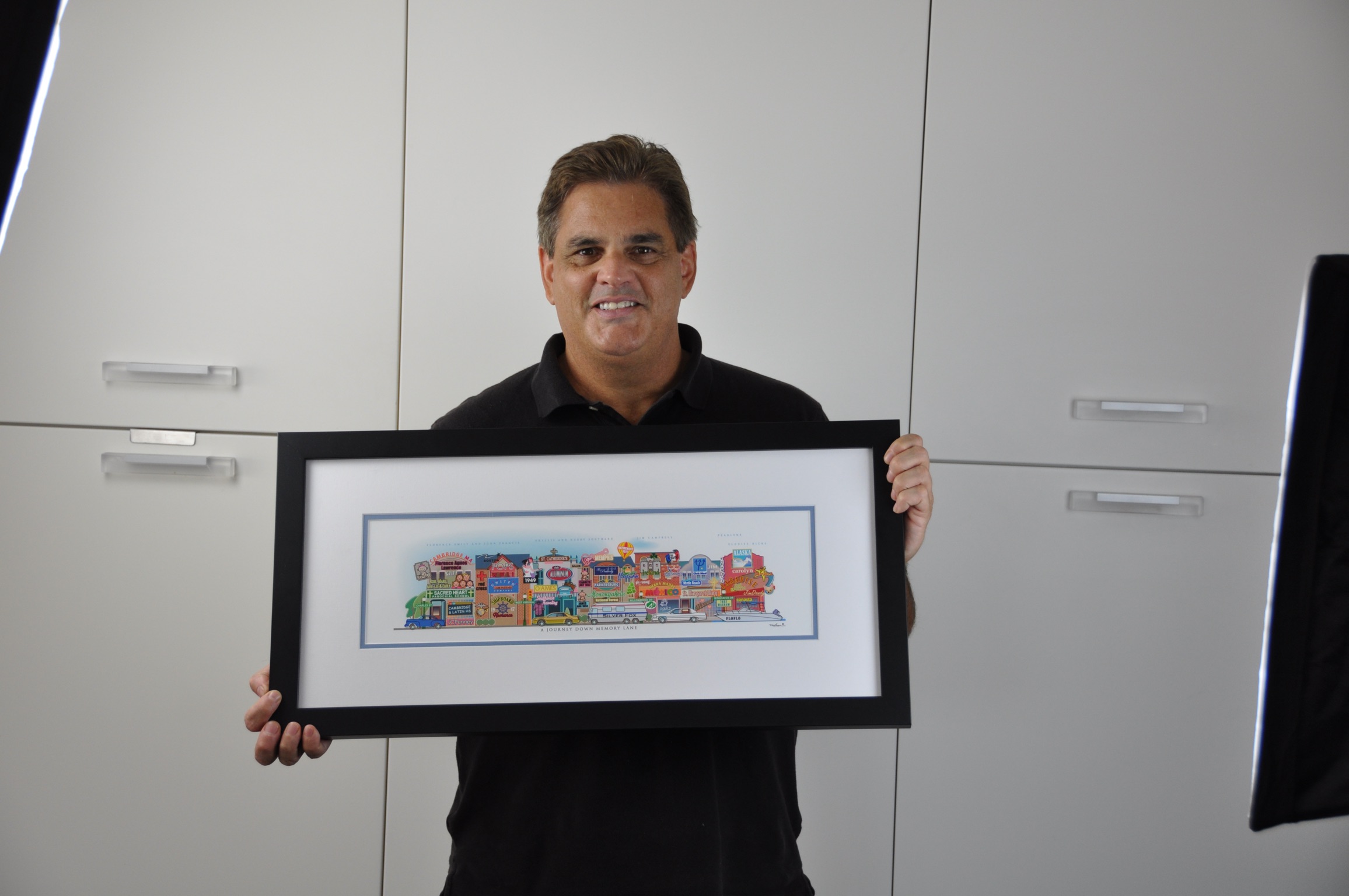 A man holding his framed Your Memory Lane retirement street print.