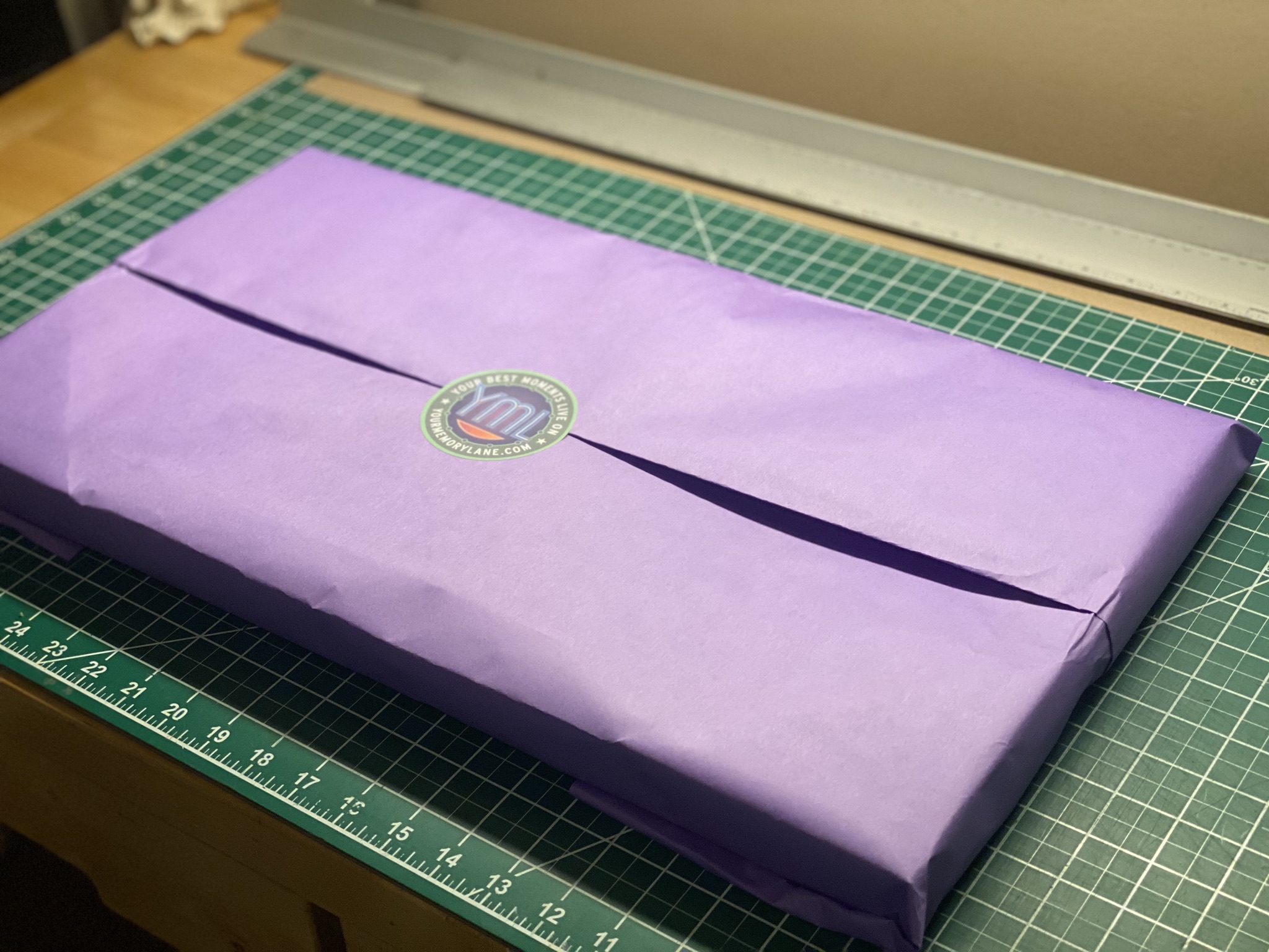 A finished print wrapped in purple tissue with the Your Memory Lane seal, ready to ship.