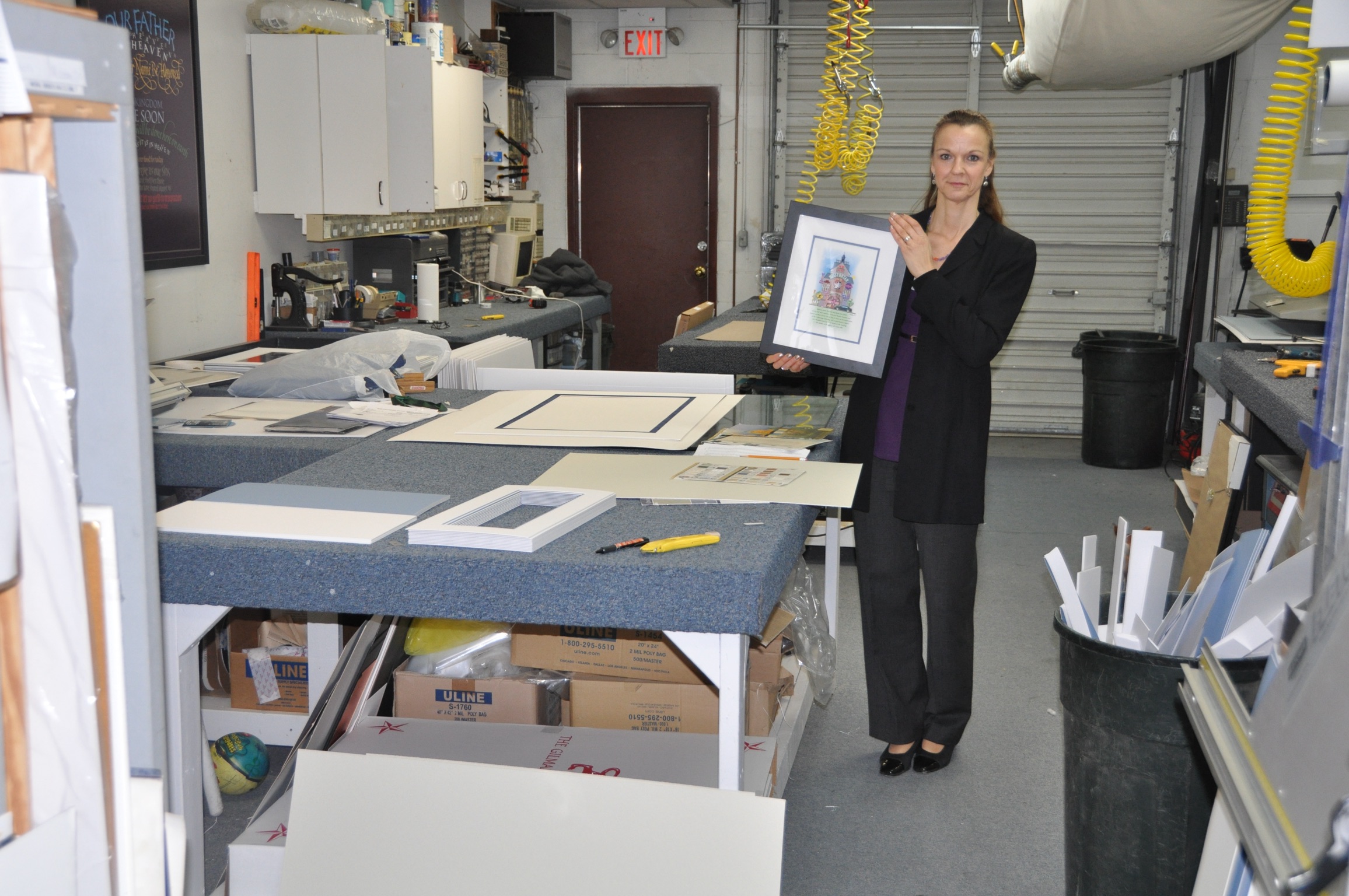 A member of the studio team holding a finished, framed Your Memory Lane print in the workshop.