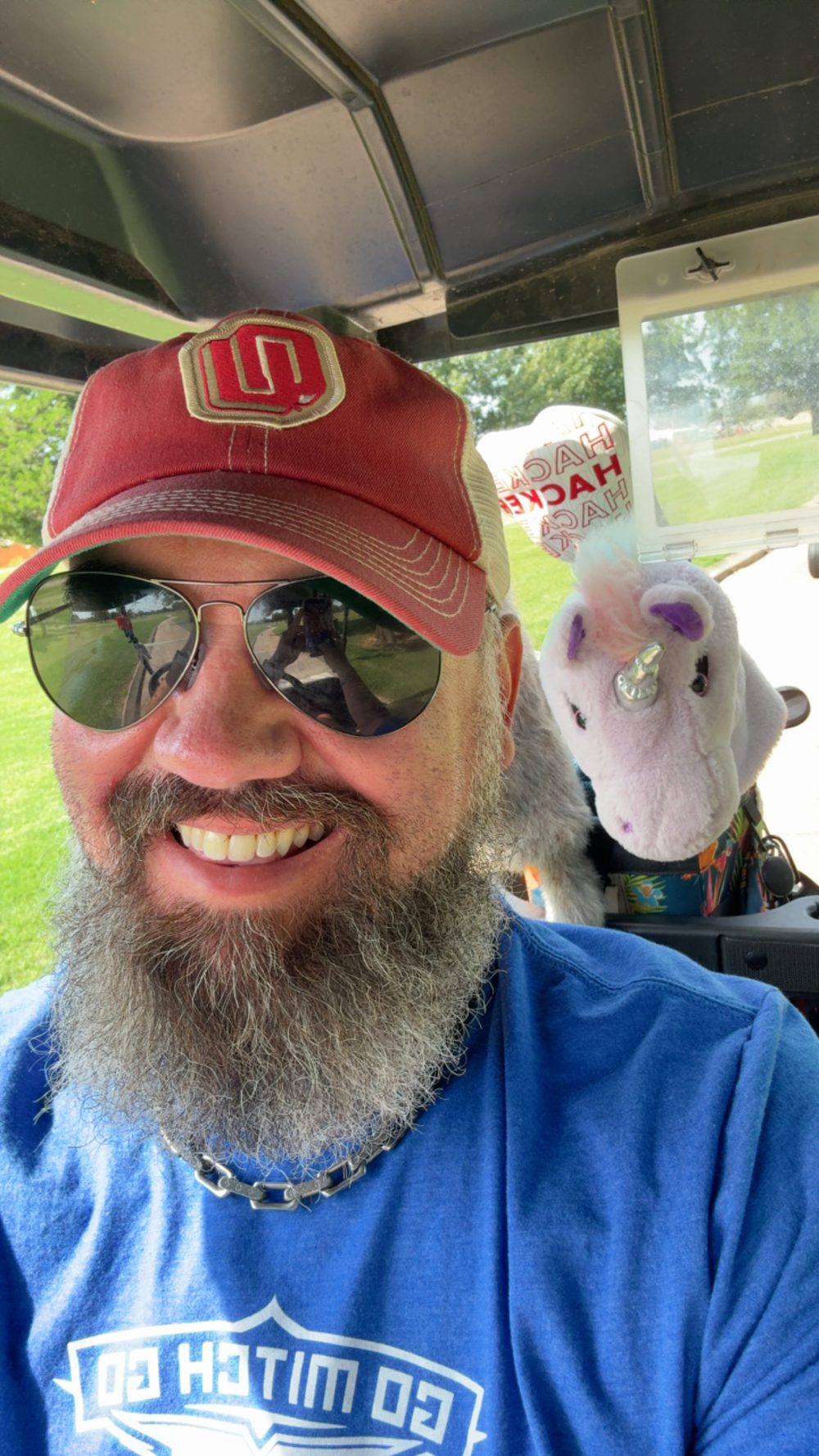 Jon in a golf cart with his unicorn club cover