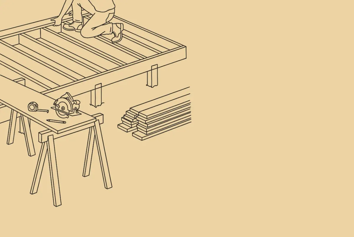 An ink drawing of a new deck frame. A carpenter's boots and knees on the joists, a circular saw, a tape measure and a pencil on a board across two sawhorses, a stack of lumber, a phone on a shelf to the right.