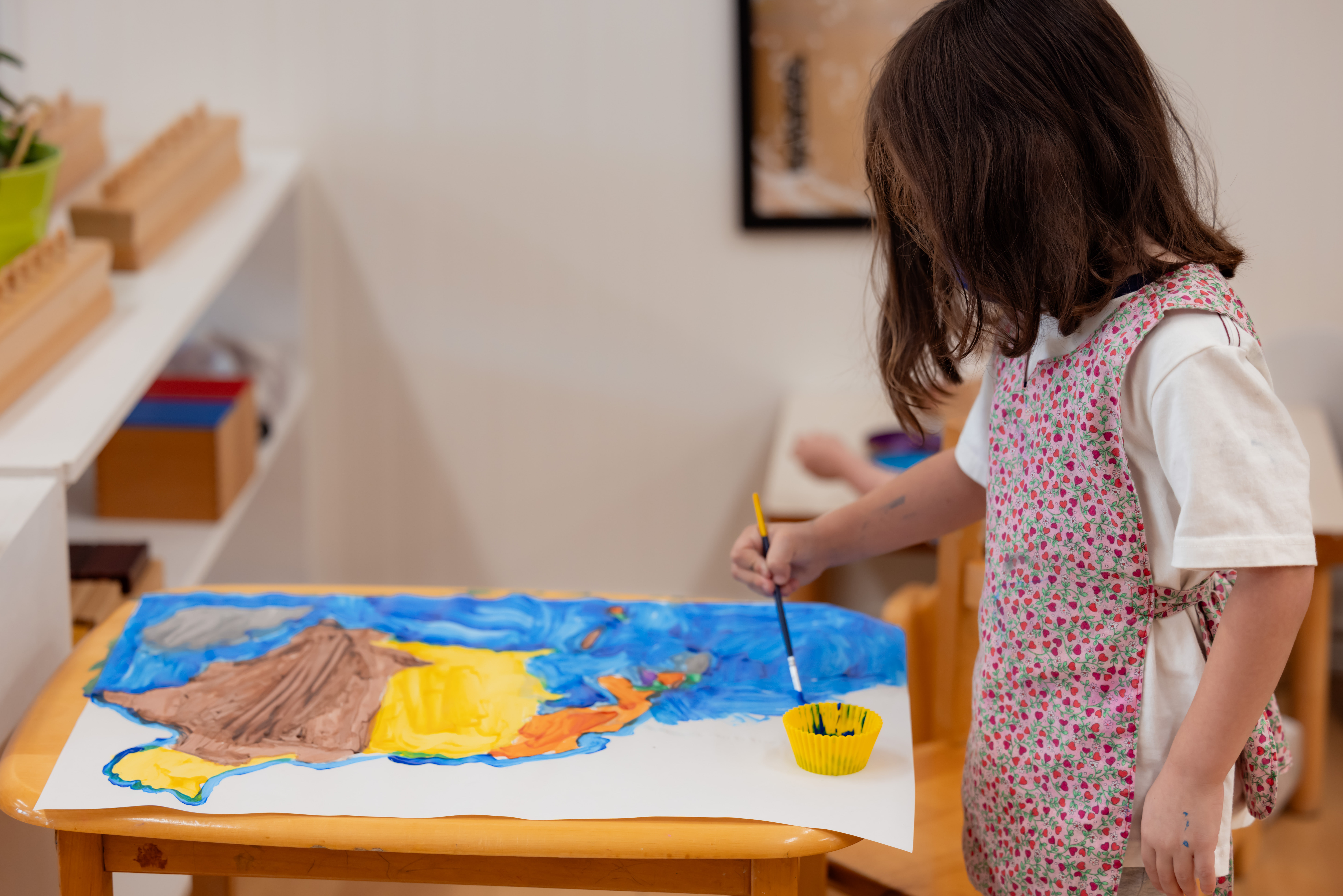 A student paints a world map in a Montessori classroom