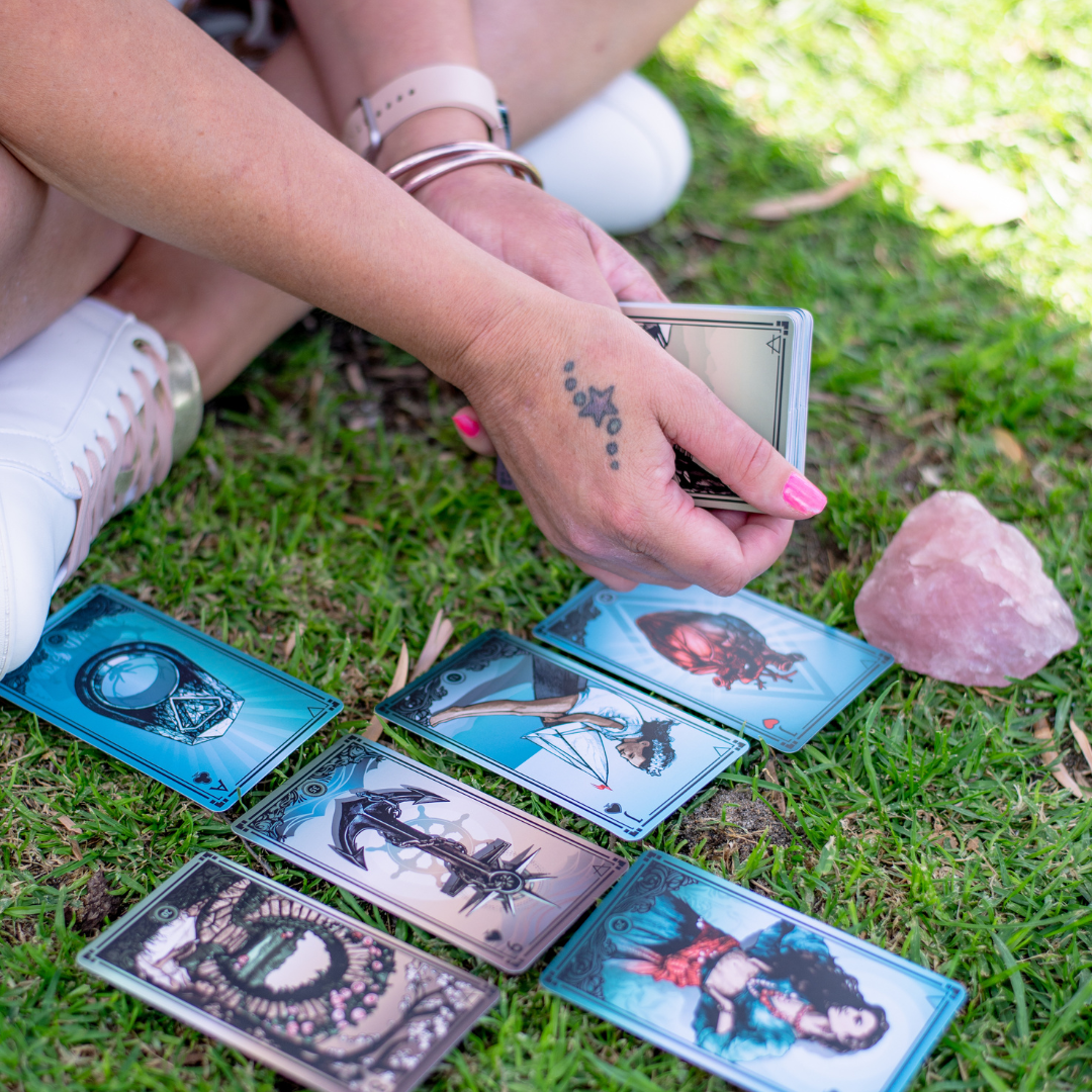 Gypsy Cards laid out on grass with woman holding them and contemplating them