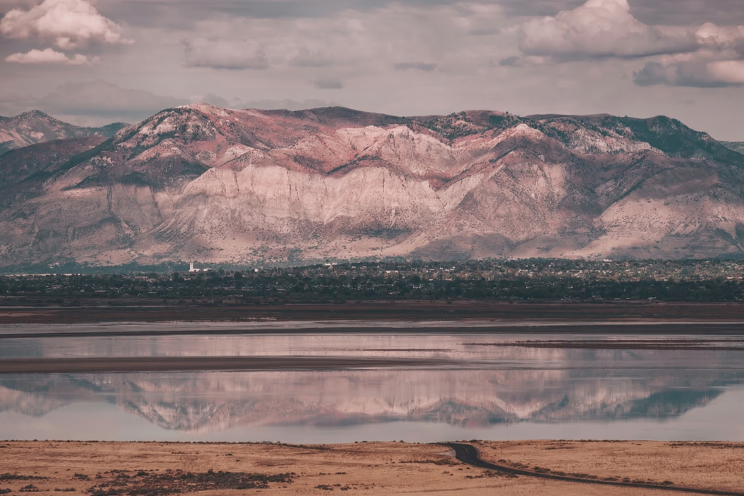 Views of mountain peaks and the city of Syracuse from Antelope Island State Park in Utah, USA. Water reflections, traveling road, Great Salt Lake. Views of mountain peaks and the city of Syracuse from Antelope Island State Park in Utah, USA. Water reflections, traveling road, Great Salt Lake.