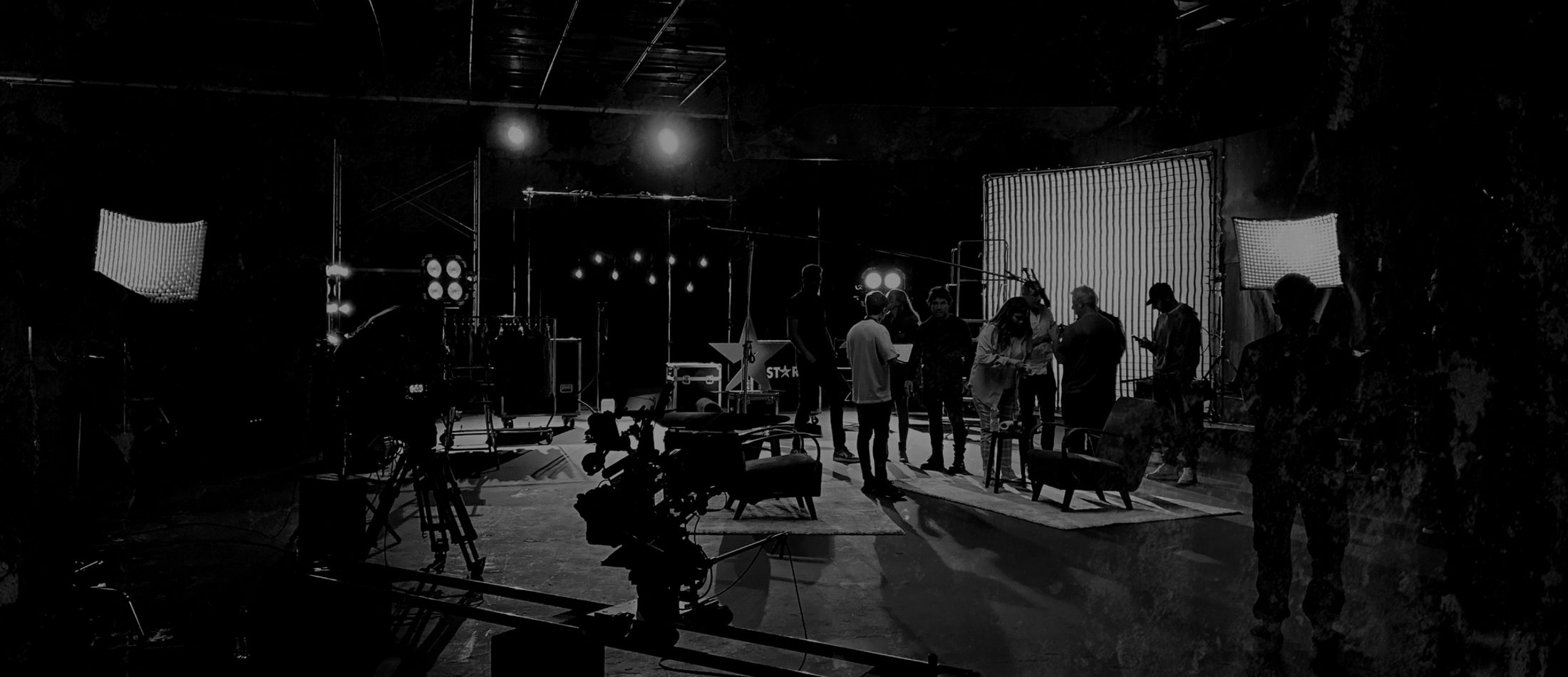 Black-and-white photo of a lit stage set with crew at work