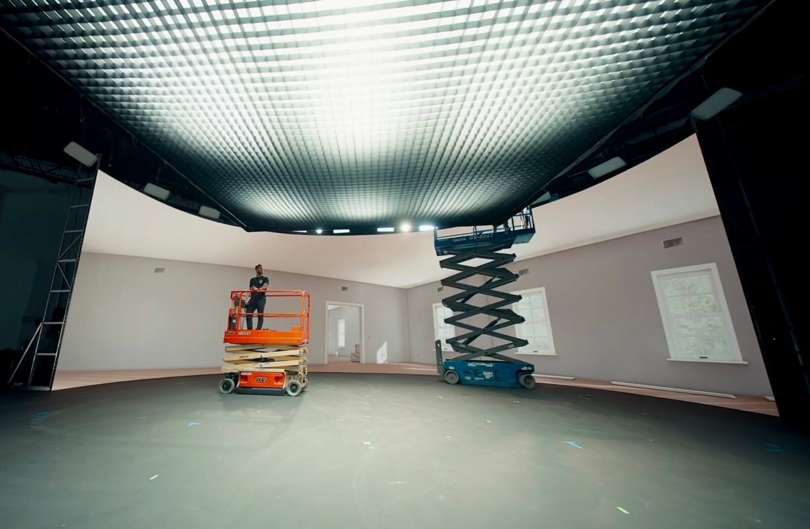 A 20 by 20 soft box glowing across a studio ceiling at BrandStar Studios, with scissor lifts below