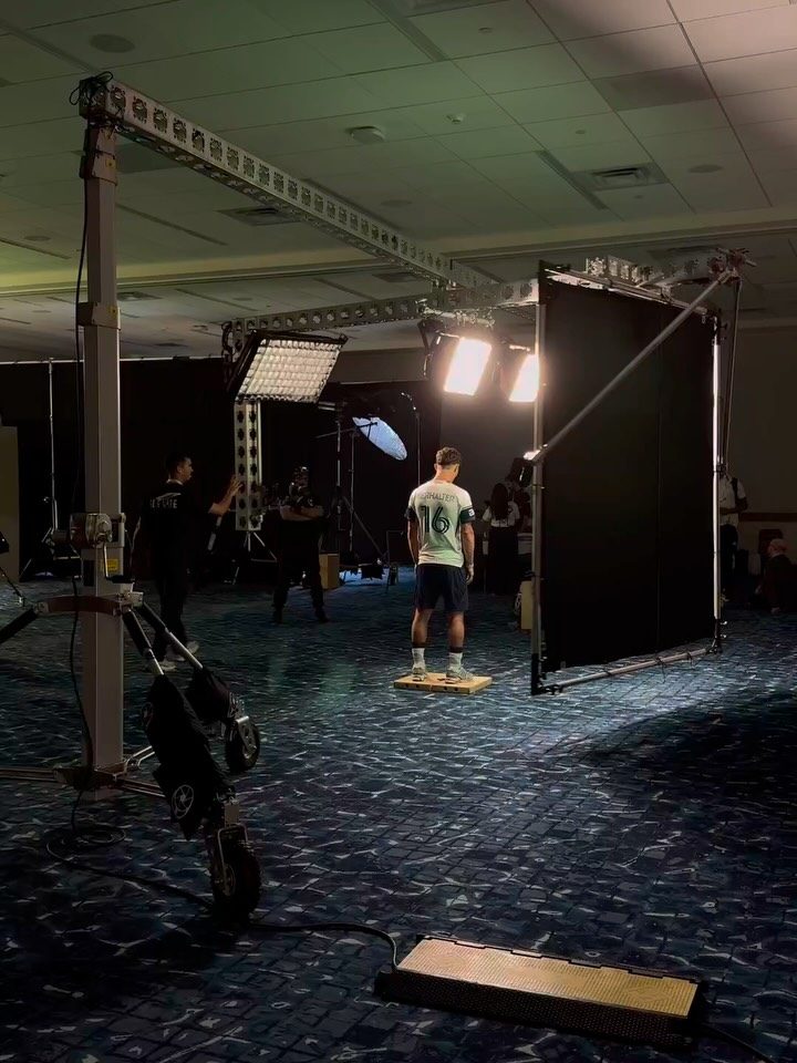 MLS Media Day set: a player on his mark under an overhead truss rig with LED panels and a black flag