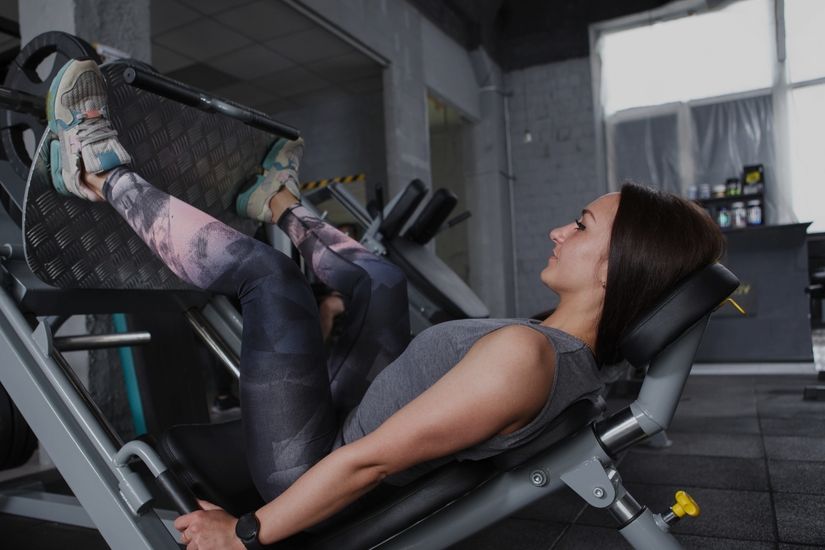 Woman performing a controlled leg press exercise in a gym demonstrating sustainable strength training. Woman performing a controlled leg press exercise in a gym demonstrating sustainable strength training.