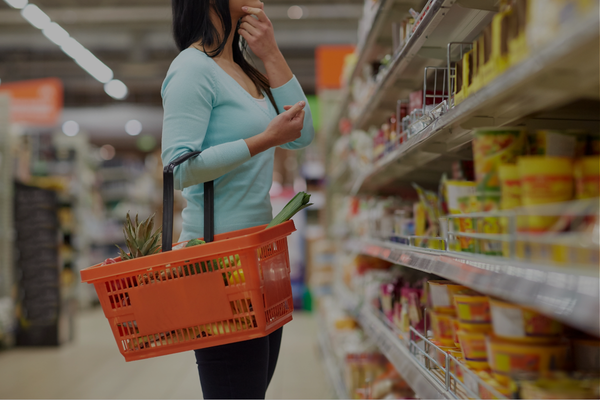Woman grocery shopping and reading food labels as part of building healthier nutrition habits during perimenopause. Woman grocery shopping and reading food labels as part of building healthier nutrition habits during perimenopause.