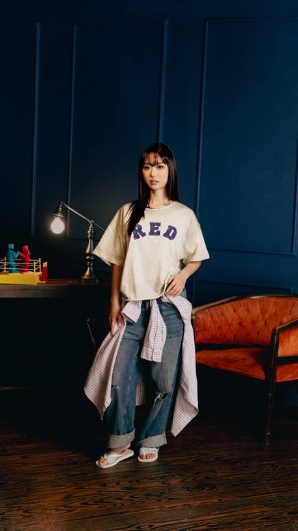 Model in a red graphic tee in a deep-blue interior