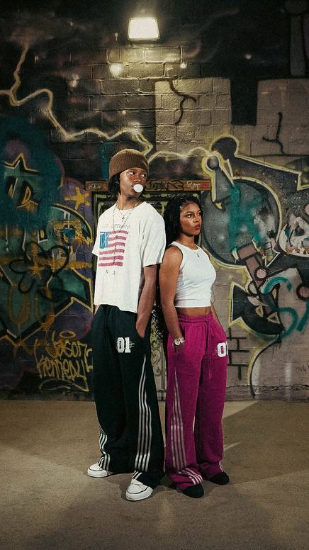 Two models in graphic tees at a graffiti wall