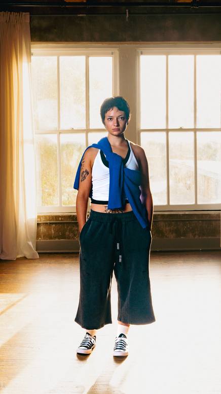 Model in wide-leg sweats backlit by a loft window