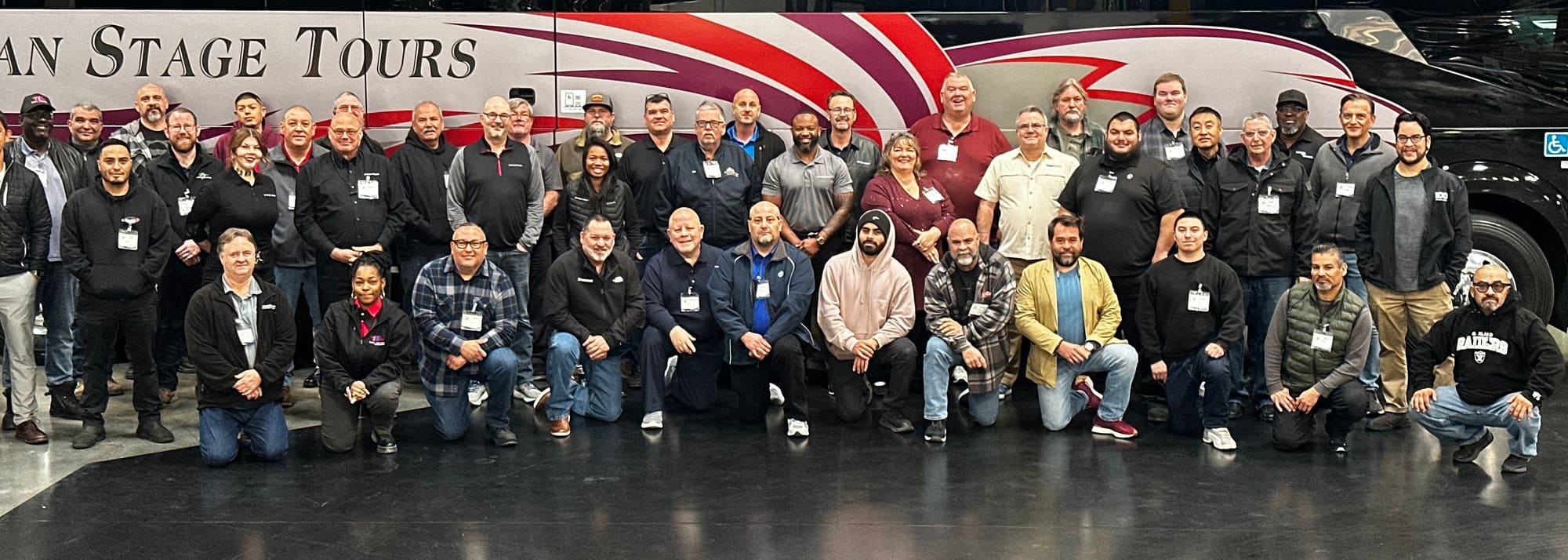 The American Stage Tours team, around forty drivers and office staff, lined up in front of one of the coaches in the depot.