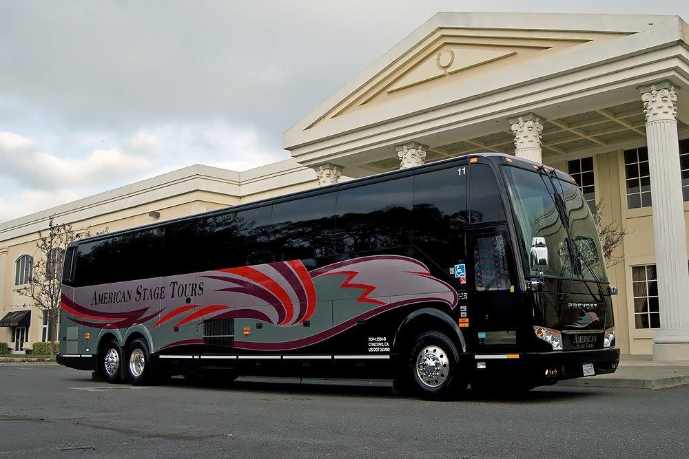 An American Stage Tours coach and its driver on the road.
