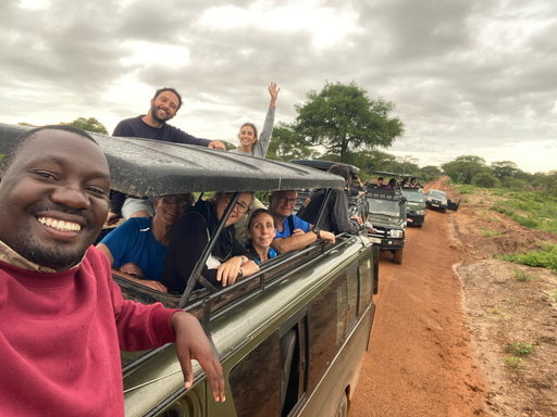 A Viajes Matatu guide talking with travellers beside the safari vehicle