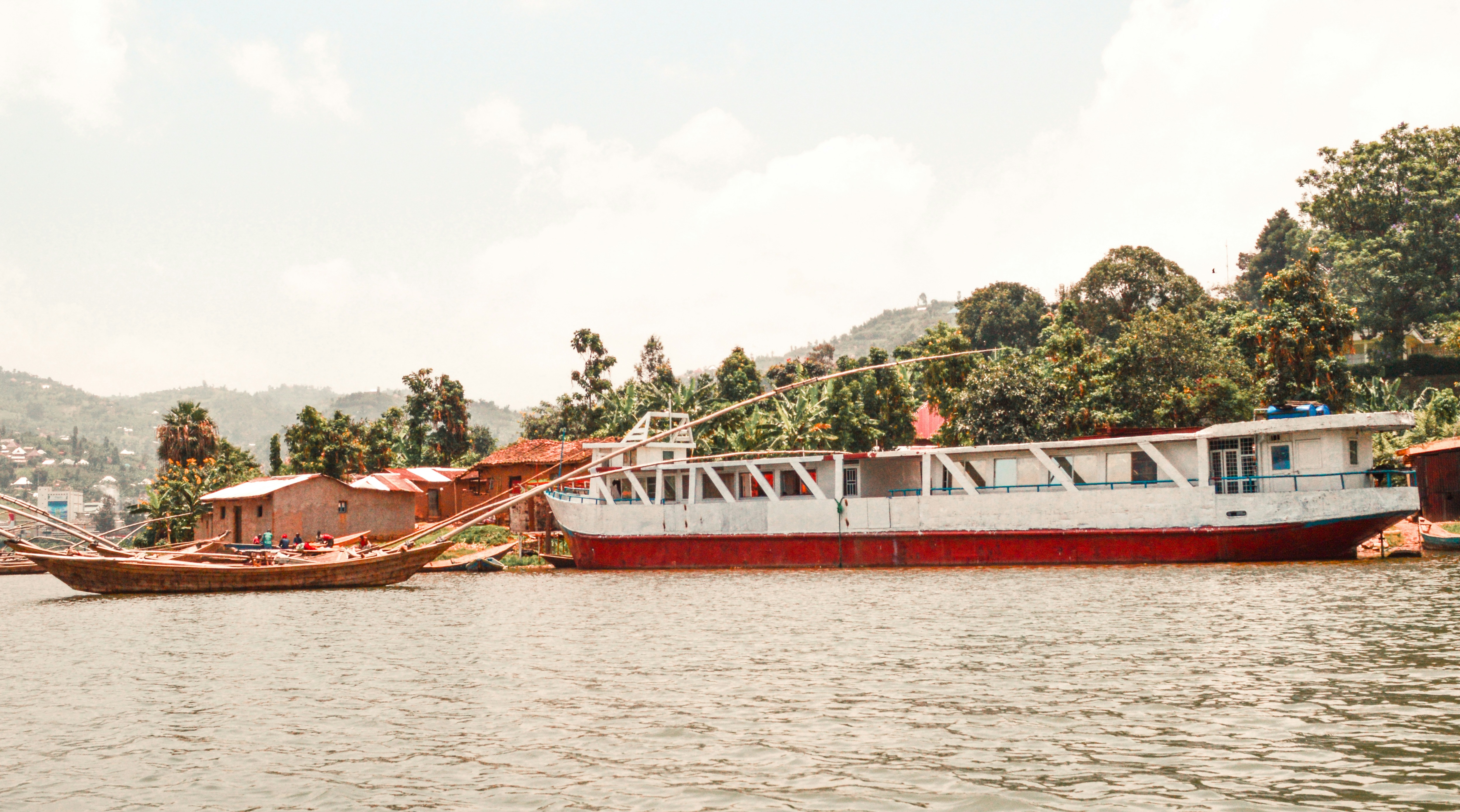 Orilla del lago Kivu, con embarcaciones amarradas y casas de tejados rojos