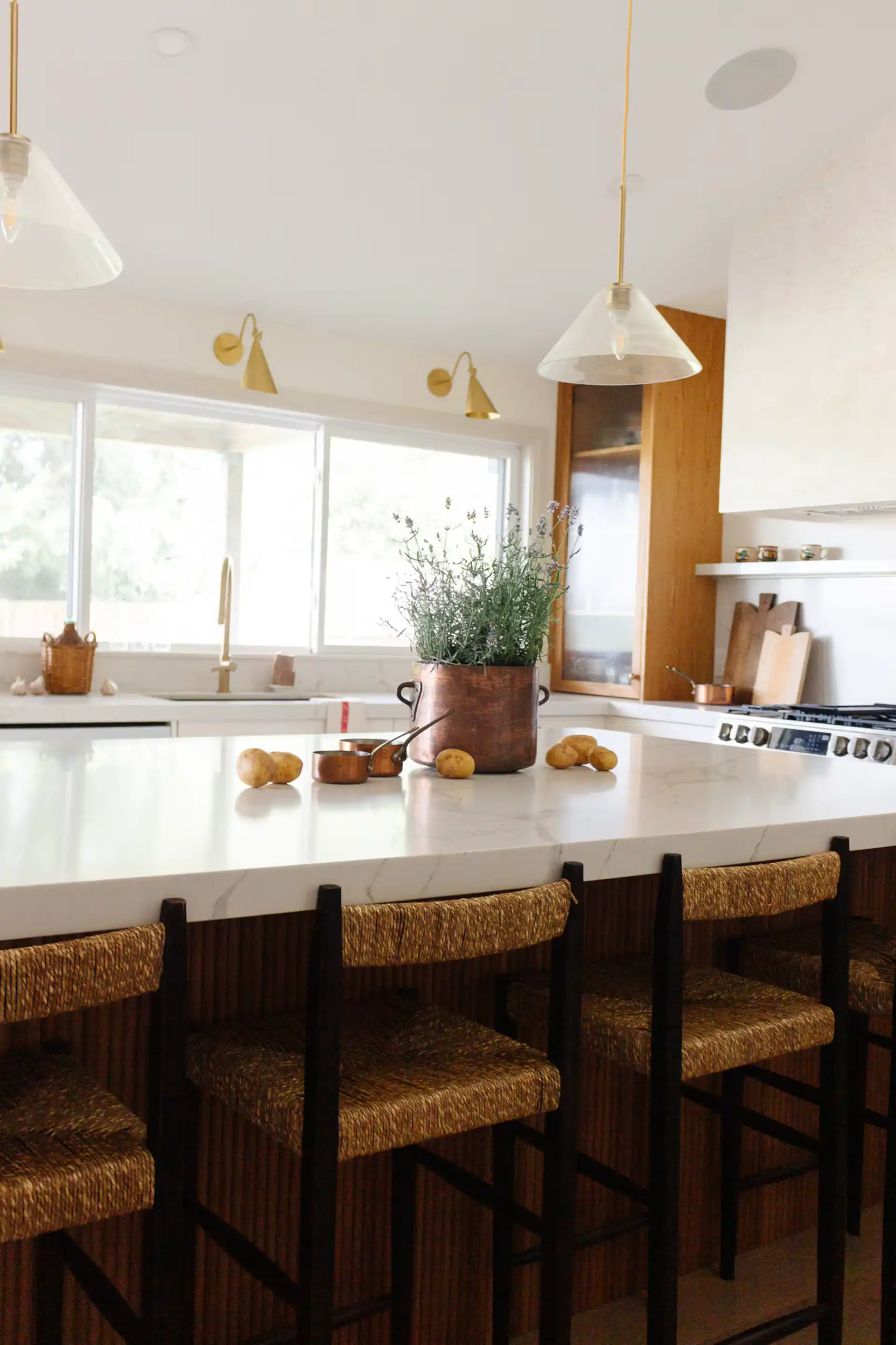 Modern luxury kitchen at The White House featuring a large waterfall island, pendant lighting, and elegant bar seating.