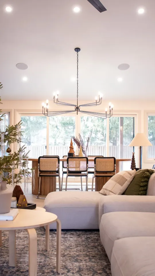 Modern open-concept living room at The White House with a luxury sectional, designer chandelier, and bright dining space.
