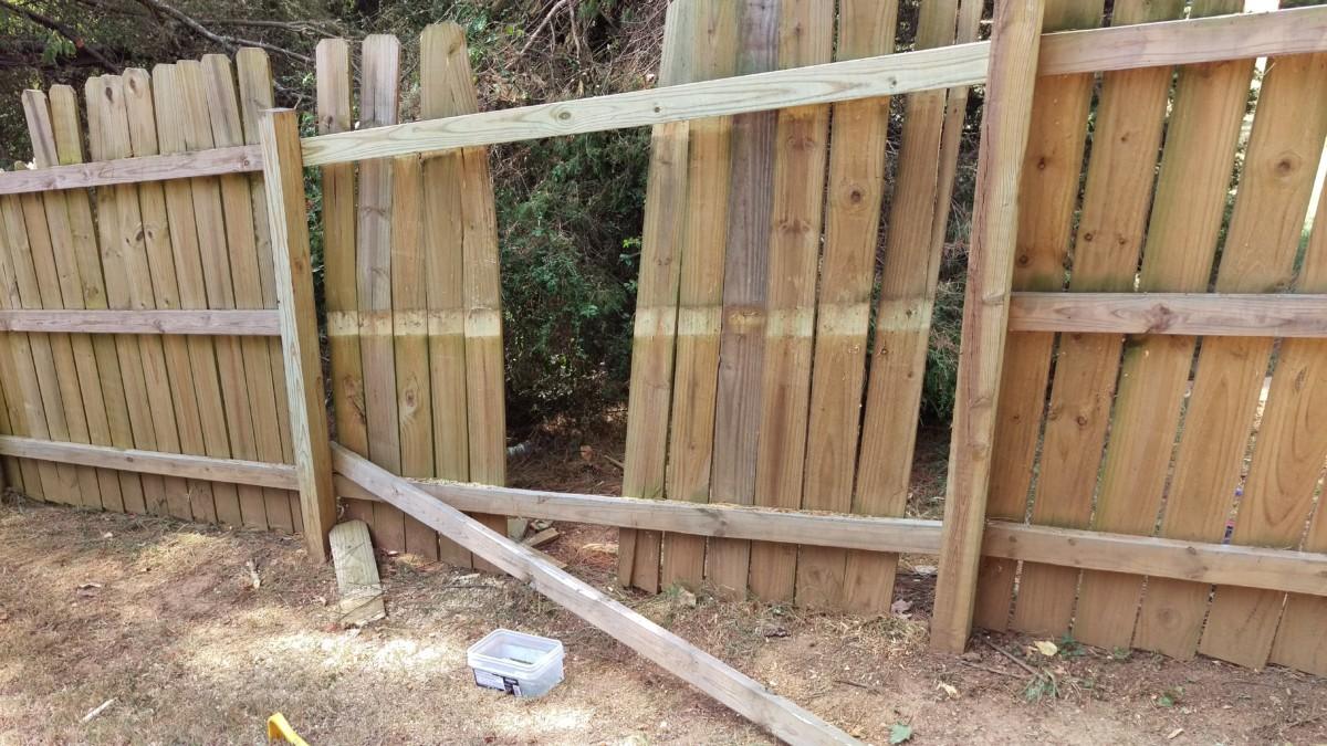 Storm-damaged wood fence panel down in a backyard