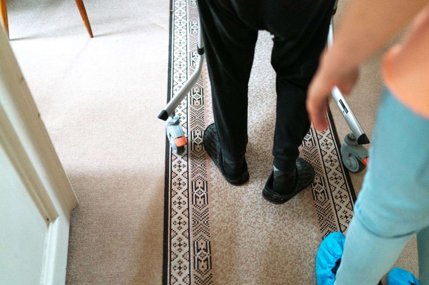 Older adult using a walking aid with support nearby