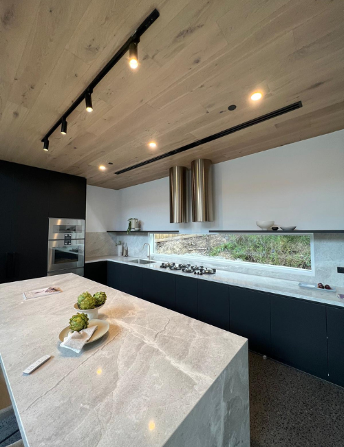 Contemporary kitchen with marble counter and black fire sprinkler on timber ceiling