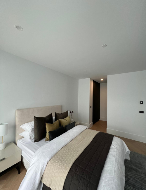 Modern bedroom featuring discreet white fire sprinklers on a white ceiling