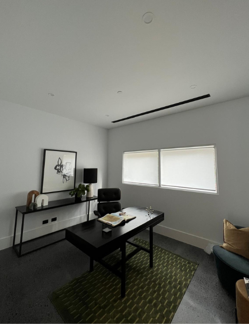 Stylish office with white fire sprinkler on white ceiling above black desk setup