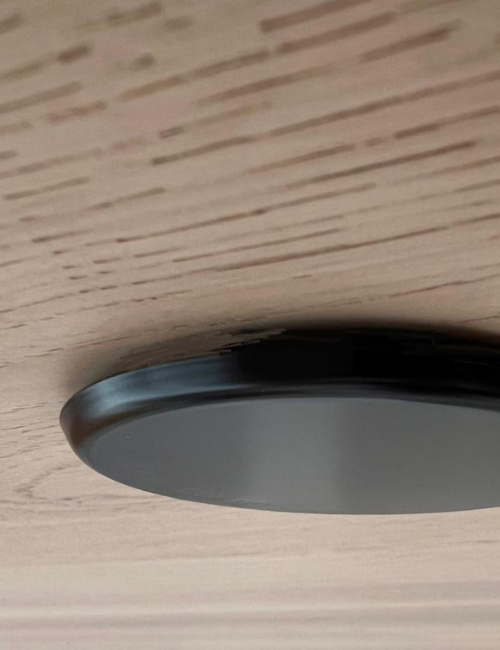 Close-up of a black fire sprinkler mounted on a wooden ceiling