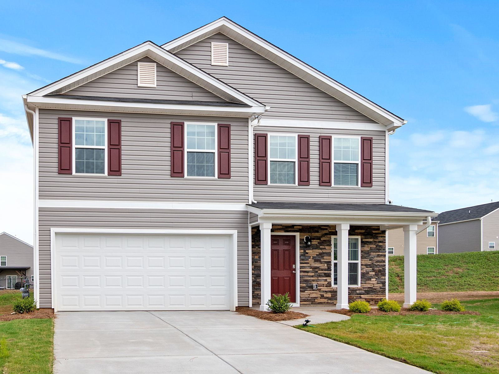 Two-story house with gray siding, red shutters and an attached two-car garage