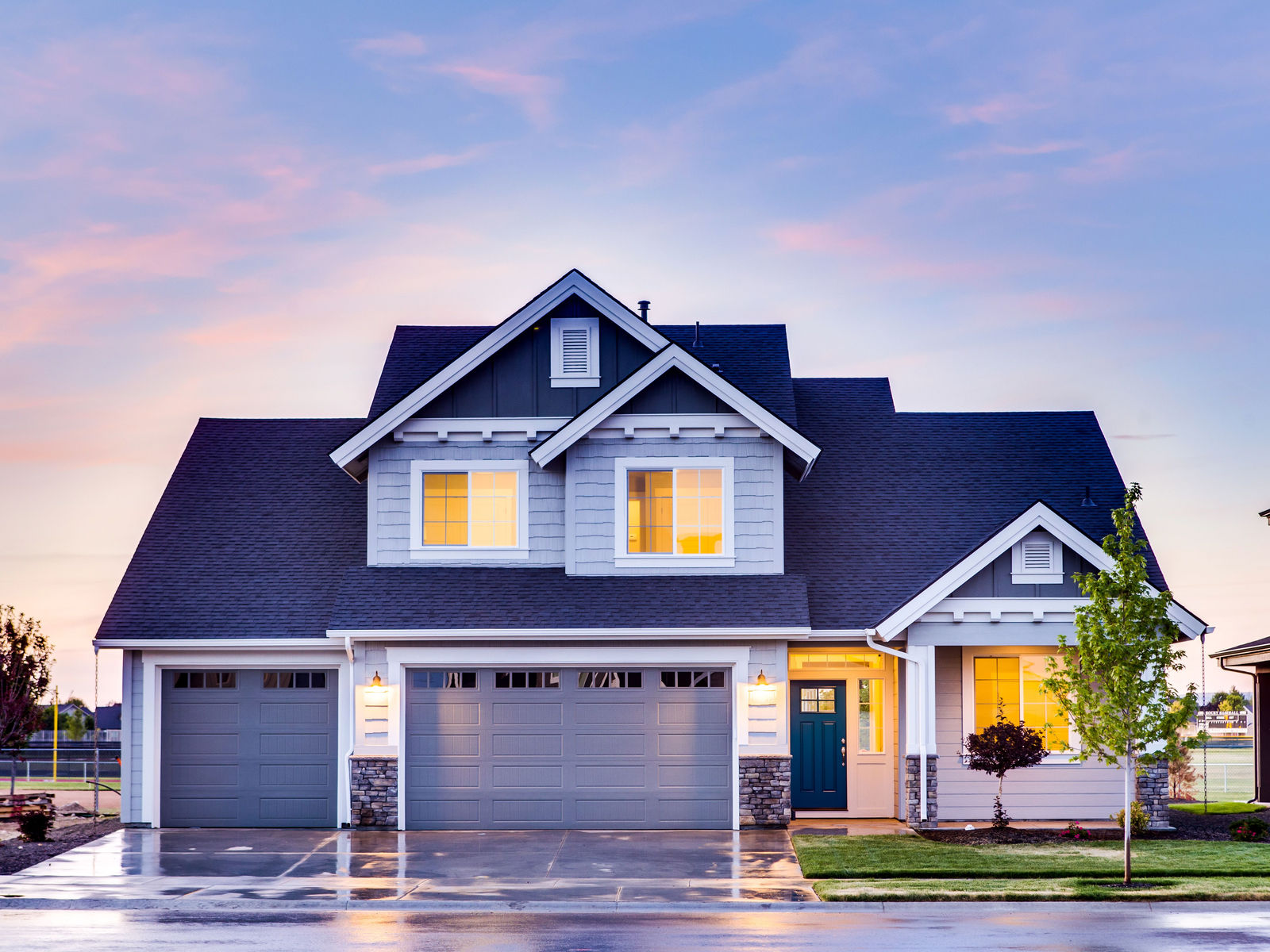 Two-story suburban home at dusk with garage lights on