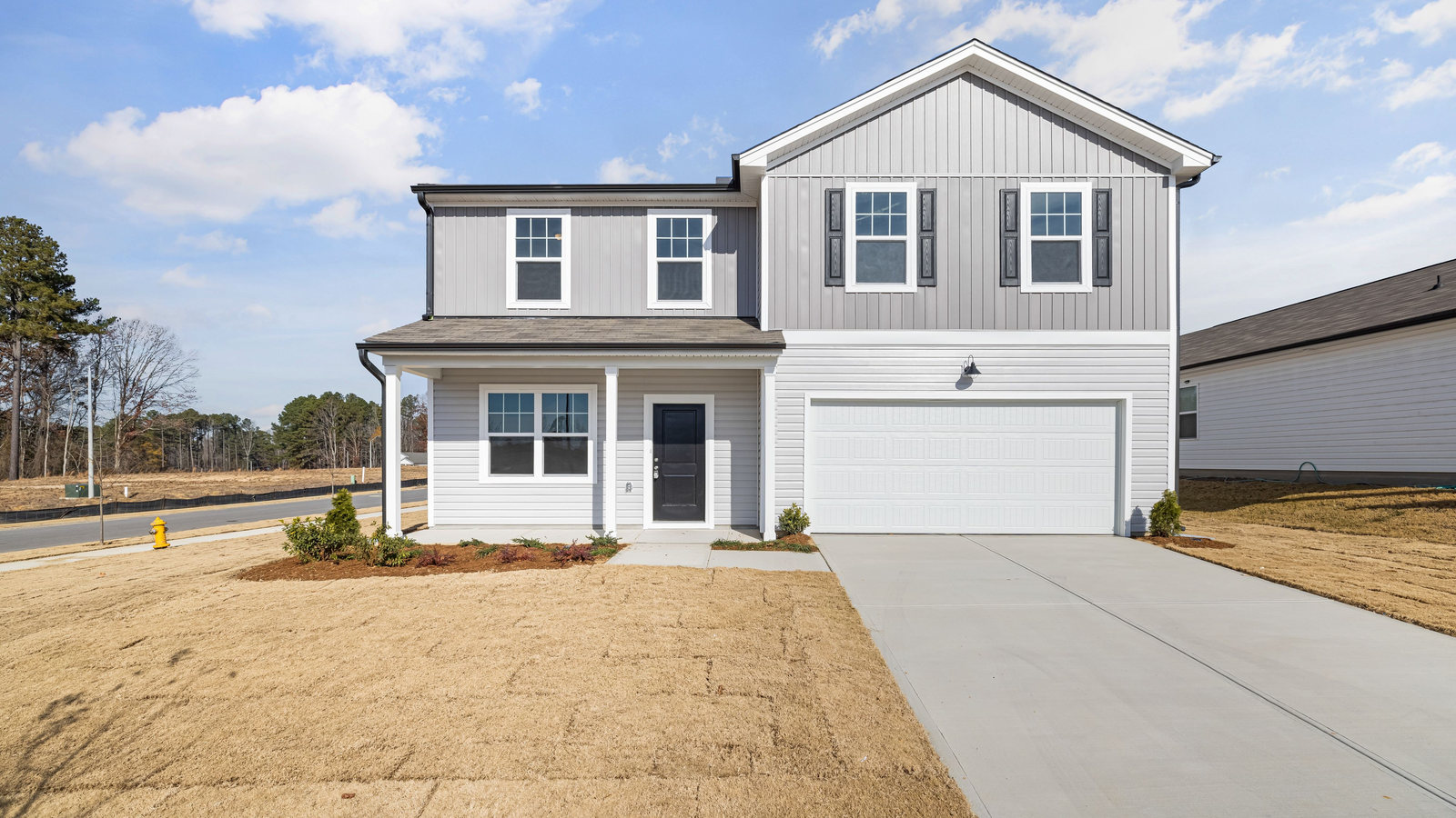 Two-story house with gray siding and an attached garage on a newer street