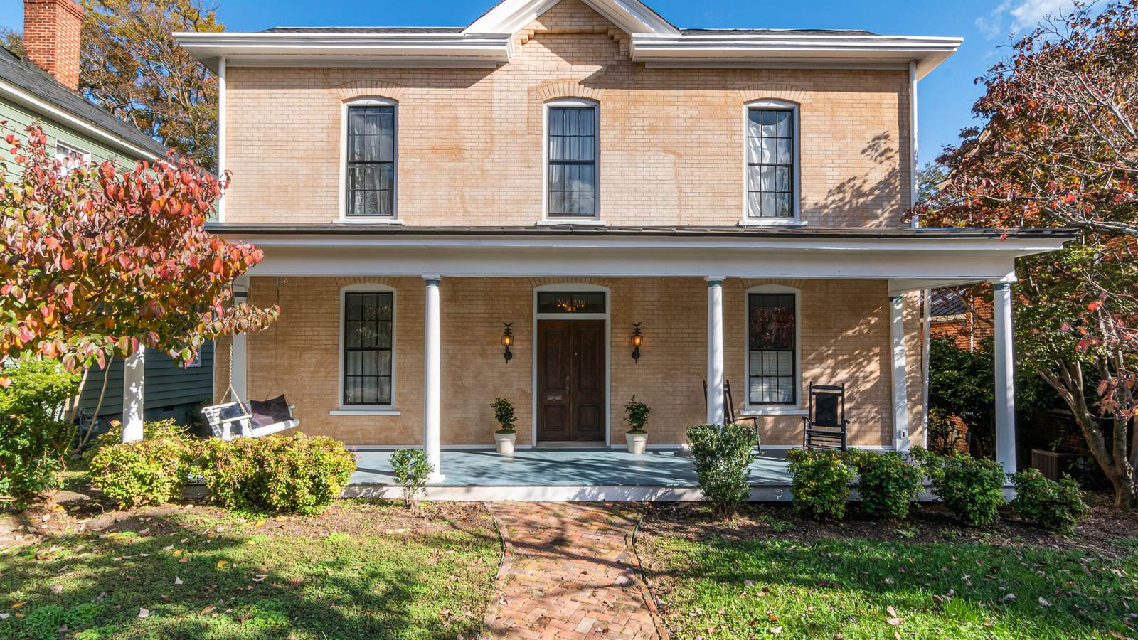 Older two-story house with a columned front porch and a brick walkway