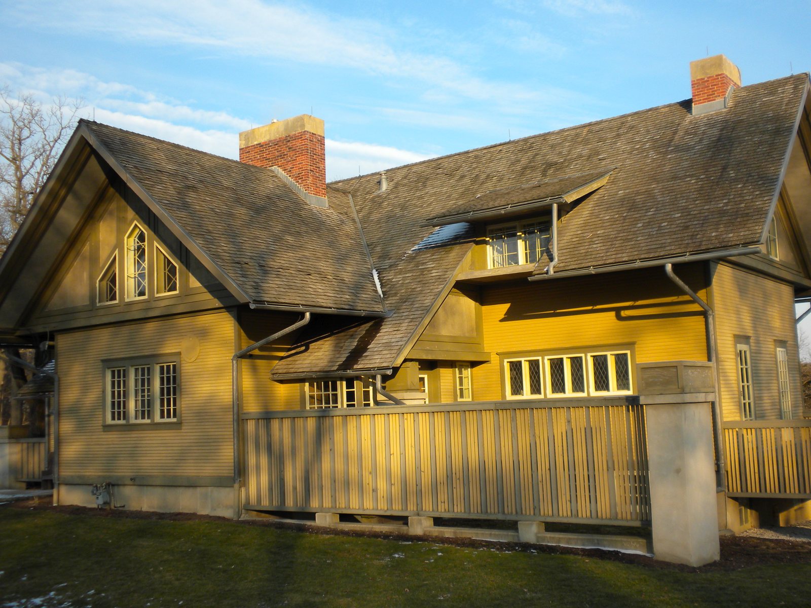 Yellow Fabyan Villa house museum in a Geneva, Illinois forest preserve, with a wooden fence in front
