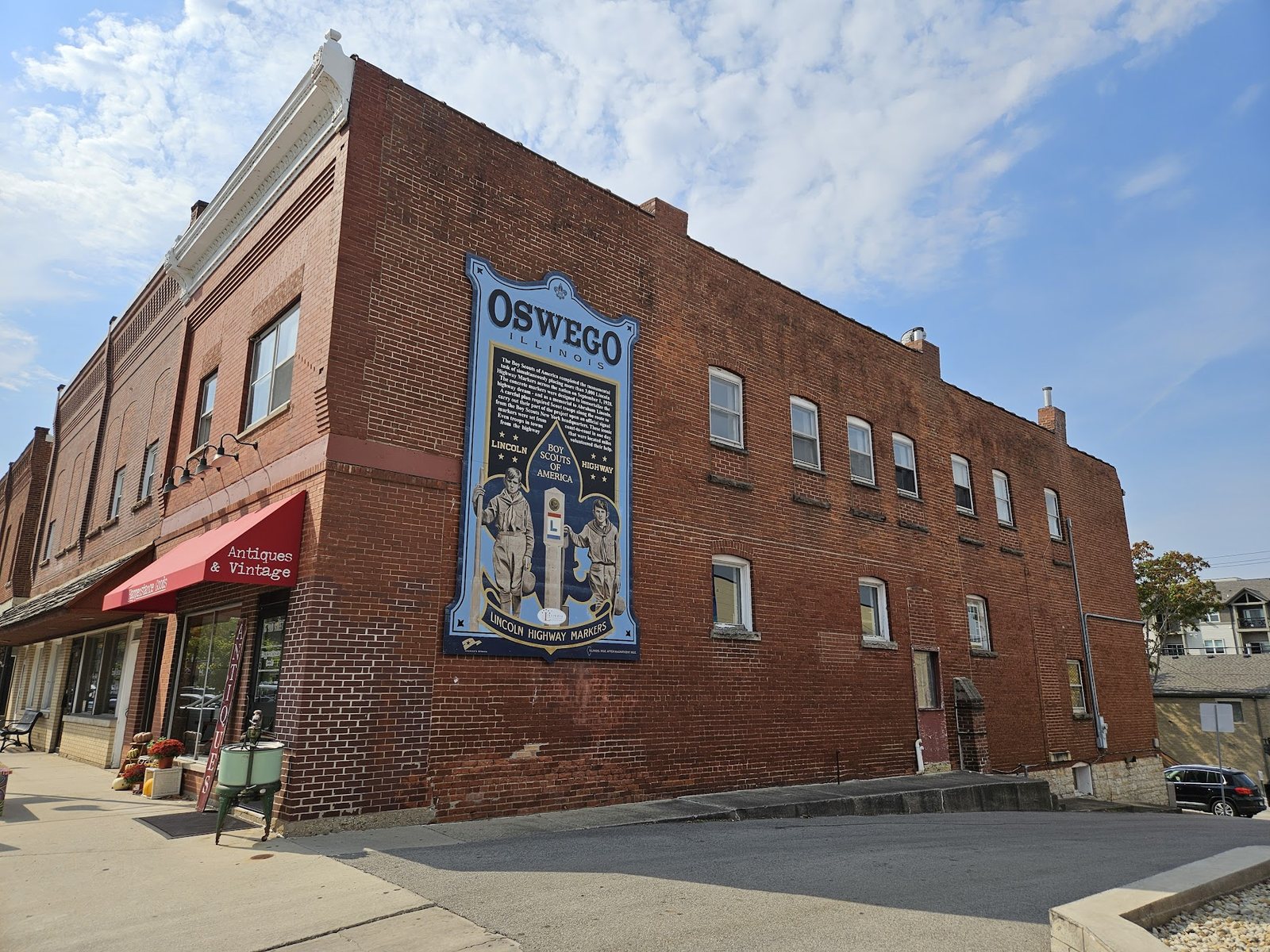 A red brick commercial building with a large Oswego mural on its side in the Downtown Oswego Historic District