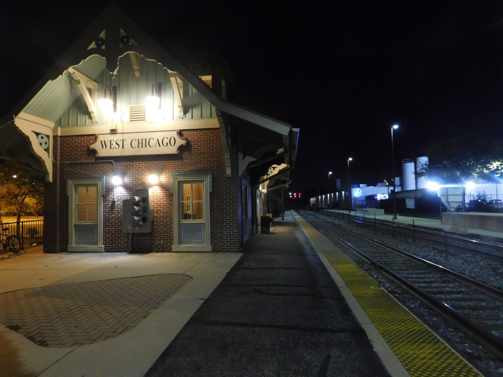 The West Chicago train station at night, with its sign lit above the platform