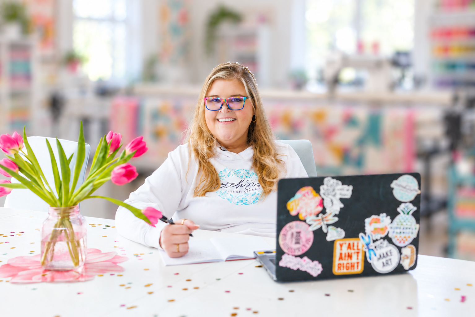 Christen smiling at her desk in her bright quilting studio